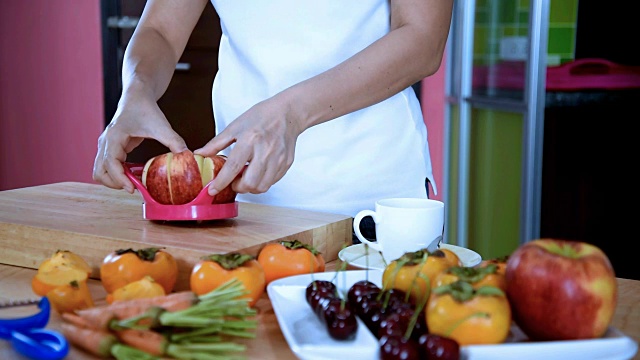 在厨房用餐具切苹果的女人/活动和健康的生活方式视频素材