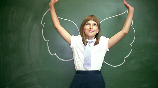 工作室肖像轻松年轻女孩站在教室的黑板前与画的天使视频下载