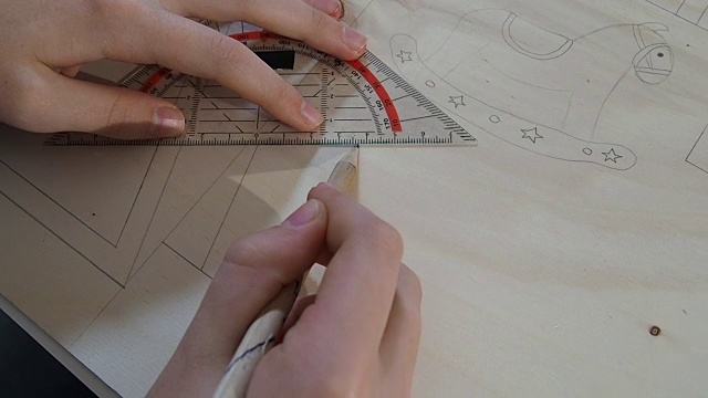 特写的女孩的手做工艺品。她在木板上借助一个角度传送带画线。视频素材