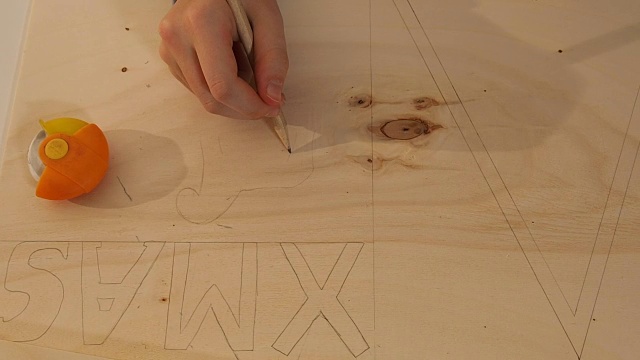 特写的女孩的手做工艺品。她在一块木板上设计并画了一匹木马。在木板上写着圣诞节。视频素材