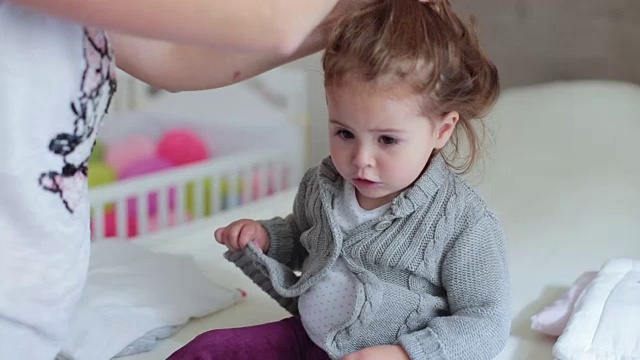 妈妈给她可爱的小女儿穿上毛衣视频下载