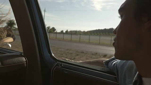 一个年轻人在车窗外挥手视频素材
