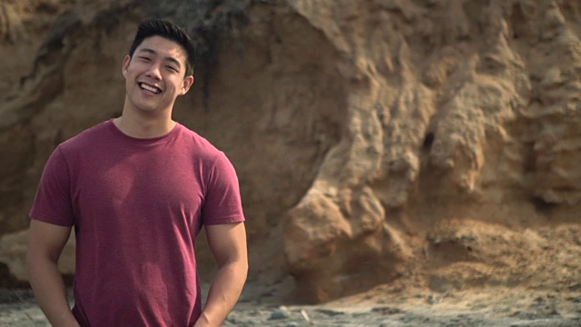 年轻的亚洲男人在海滩上微笑视频下载
