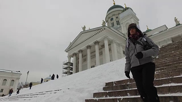 芬兰赫尔辛基，一名女子走下楼梯，背景是赫尔辛基大教堂视频下载