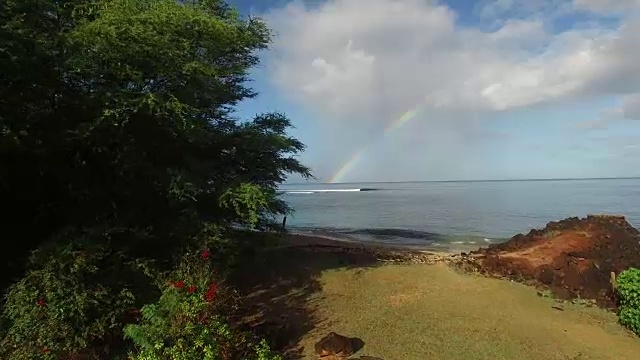 彩虹出现在夏威夷考艾岛的一个冲浪休息。当地的这个地方是偏僻的，但冲浪者可以在彩虹下找到完美的海浪。视频素材