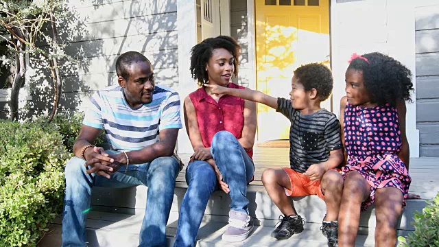 一个非裔美国家庭坐在门阶上谈笑风生视频素材