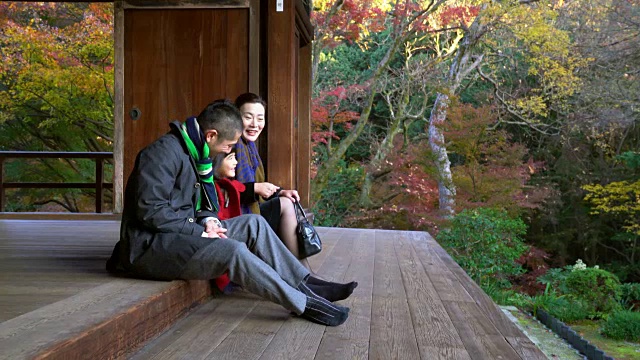 一家人坐在寺庙外面一起玩视频素材