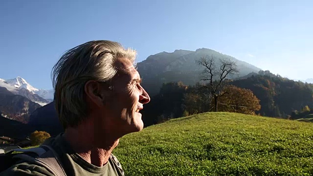 日出时分，一名男性徒步旅行者穿过山地草地视频素材