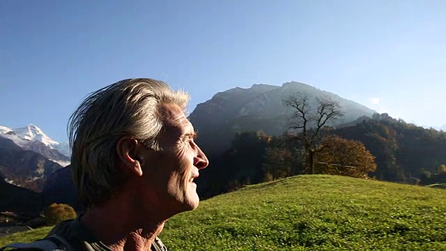 日出时分，一名男性徒步旅行者穿过山地草地视频素材