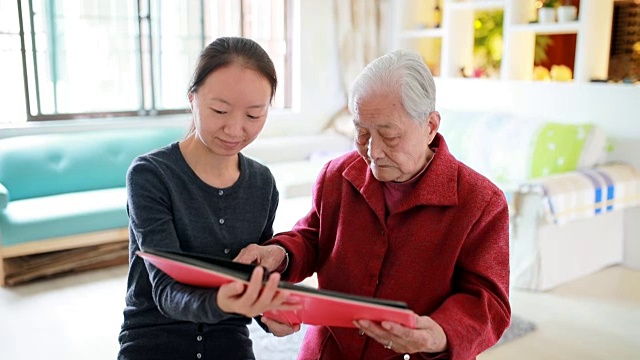 孙女和奶奶坐在一起看老照片。视频素材