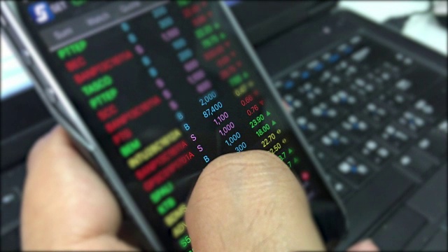 亚洲男性使用智能手机查看和分析股票趋势视频下载