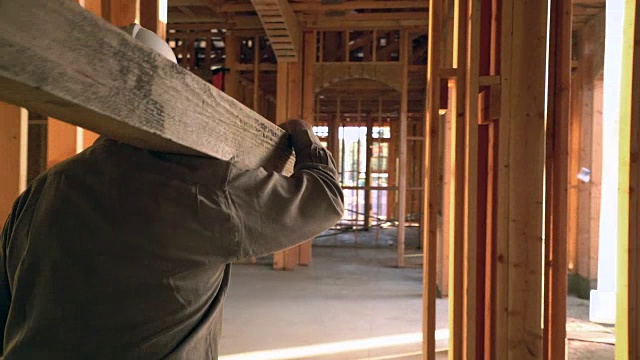 RV SM TS建造者携带一块木板通过一个建筑工地视频下载