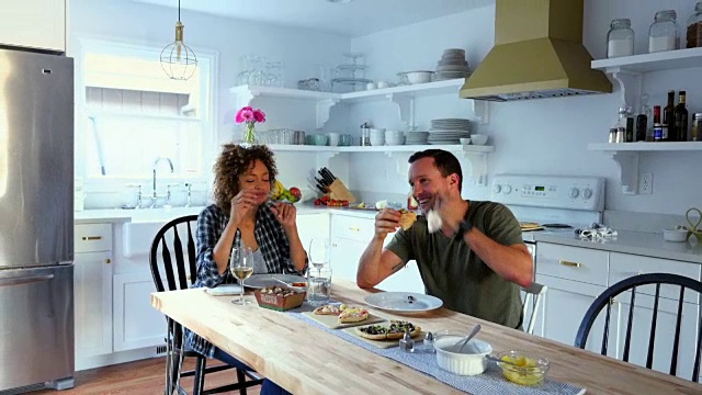 笑着的丈夫和妻子在家里的厨房里吃晚饭视频下载