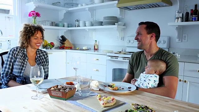 父亲抱着膝上的婴儿，与妻子在餐桌上用餐视频下载