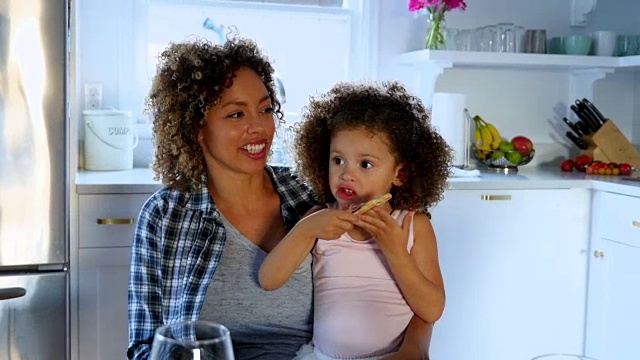 一家人在厨房吃饭时，母亲抱着女儿坐在膝上视频下载