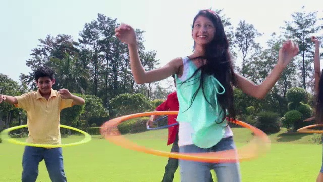 五个十几岁的男孩和女孩在印度德里的公园里玩呼啦圈视频素材