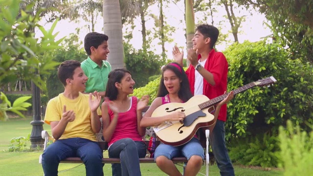 在印度德里的公园里，五个十几岁的男孩和女孩在享受音乐视频下载