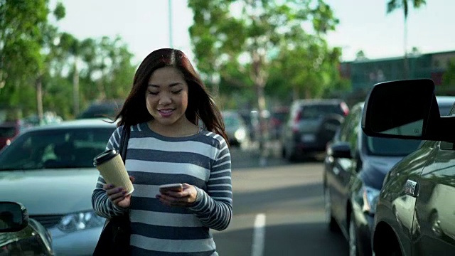 一名年轻女子拿着咖啡杯走过停车场视频下载