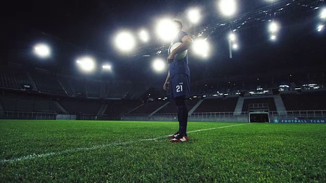 一个足球运动员晚上在空旷的体育场的肖像视频素材