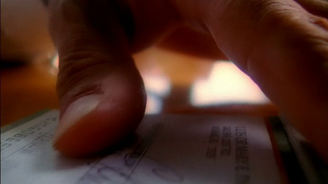 极端接近男人的手签字支票在桌子上，并从支票簿视频下载