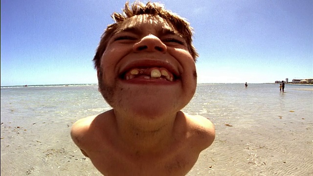 在佛罗里达迈阿密海滩上，一个中等身材的男孩看起来很严肃，然后对着镜头摆出笑脸视频下载