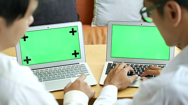 两名商人使用两款笔记本电脑，绿色屏幕，色度键视频素材