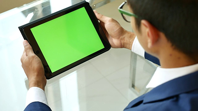 过肩拍摄使用绿色屏幕的数字平板电脑，色度键视频素材