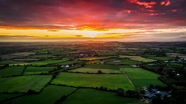 爱尔兰，空中的乡村景观与田野和农田在戏剧性的日落天空下视频下载