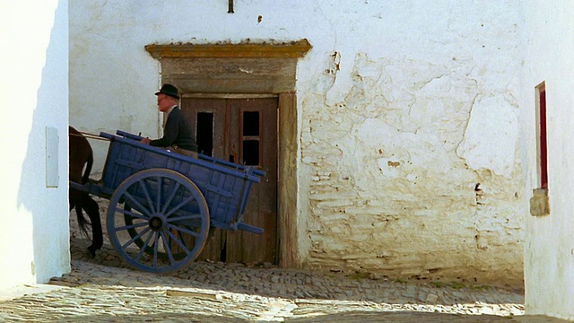 葡萄牙蒙萨拉兹，在狭窄的村庄街道上，一名骑着驴拉着车的男子视频素材