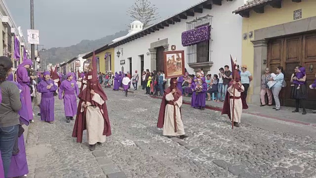 危地马拉安提瓜的天主教大斋节复活节游行。身穿传统紫色和带帽服装的人们抬着的雕像视频下载