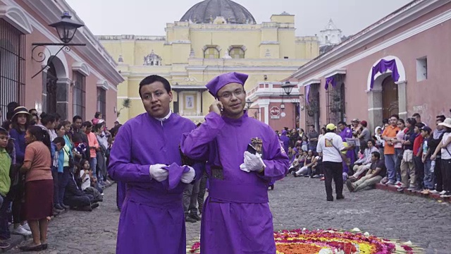 身着天主教庆典服装的男子正在打电话。在游行过程中，他穿着紫色的传统服装，这是危地马拉安提瓜大斋节复活节庆祝活动的典型装束。视频下载