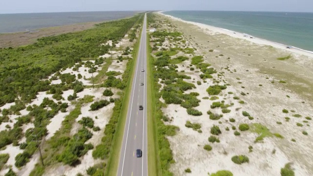 美国北卡罗来纳州哈特拉斯角，汽车在路上行驶，背景是海滩视频下载
