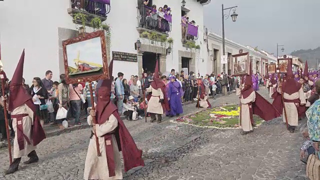 危地马拉安提瓜的天主教大斋节复活节游行。身穿传统紫色和带帽服装的人们抬着的雕像视频下载