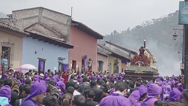 危地马拉安提瓜的天主教大斋节复活节游行。身穿紫色和黑色传统服装的人们抬着的雕像视频下载