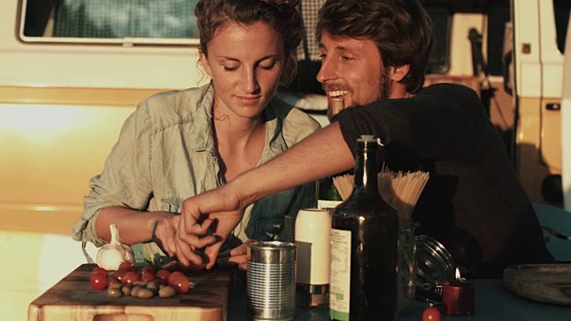 在法国南部的一个露营地，一对相爱的年轻情侣在大众汽车前享受时光，准备食物，切蔬菜视频下载