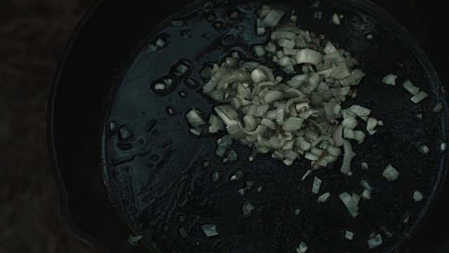 洋葱和大蒜在油在铸铁锅。视频下载
