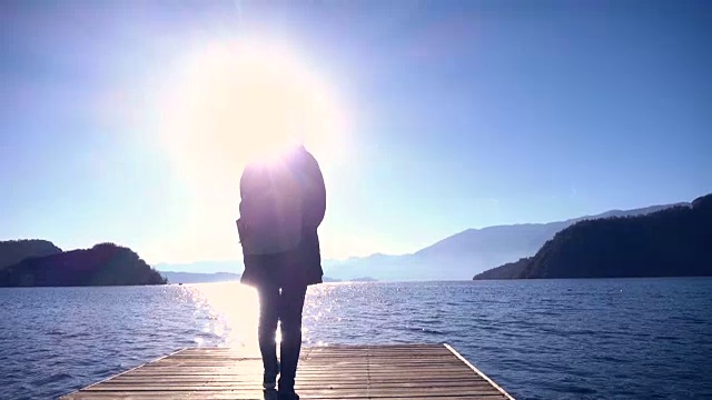 一个女人走在木码头上的湖边视频素材