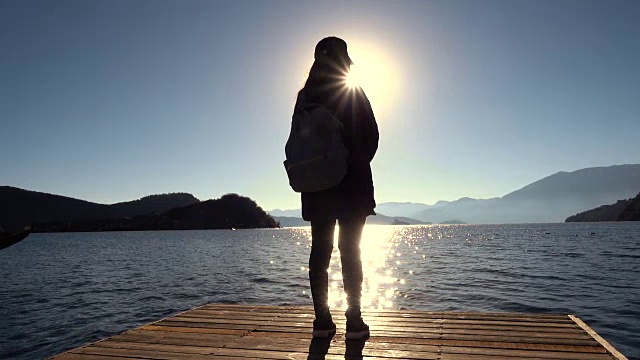 一个女人走在木码头上的湖边视频素材