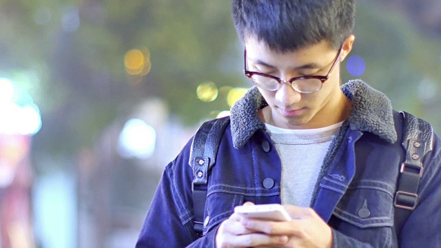 亚洲男子学生晚上在校园里拿着手机视频素材