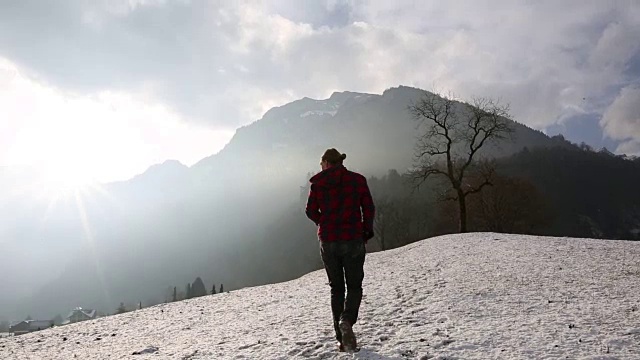 人类爬上了山上被雪覆盖的草地视频素材