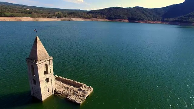 无人机拍摄的航拍画面显示，这座紧急教堂淹没在加泰罗尼亚地区Sau水库的水中。4 k UHD。视频素材