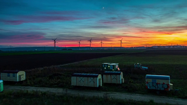 在引人注目的日落天空下，用风力涡轮机飞越乡村景观视频素材