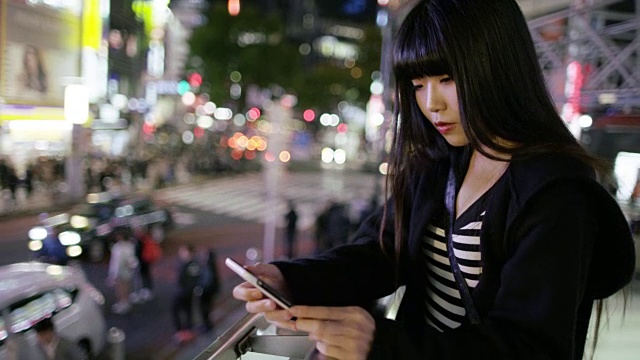 在日本东京涩谷，一名年轻的日本女子在查看手机视频素材