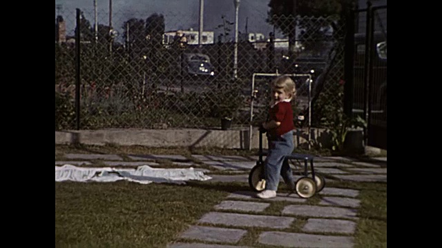 1949年，一个小女孩在前院骑三轮车视频素材