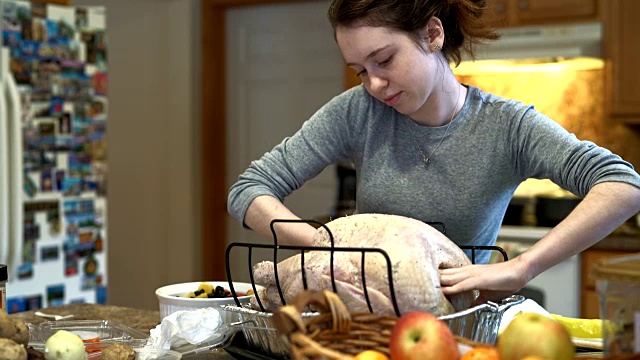 十几岁的女孩正在为节日家庭晚餐填火鸡。视频素材
