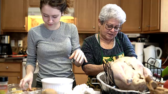 一个十几岁的女孩，一个孙女，还有她的祖母，一个满头银发的老妇人，正在为节日晚餐填火鸡视频下载