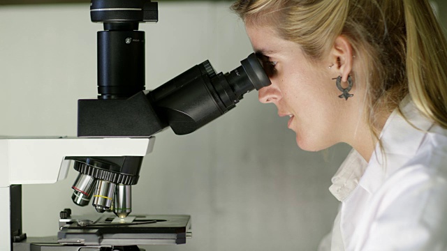 一个女人在实验室里看显微镜视频素材