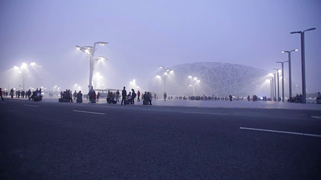 北京，Сhina——2016年10月14日:在雾霾污染下，游客在夜间参观北京鸟巢体育场广场。视频素材