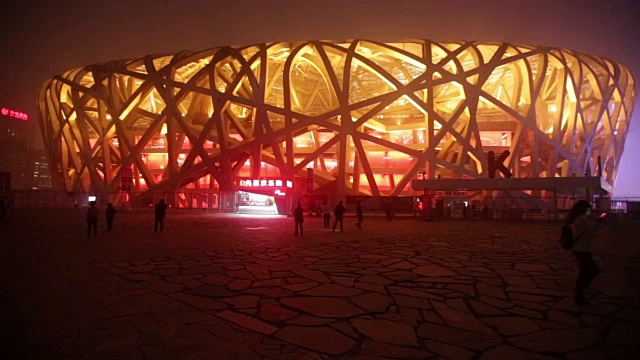 北京，Сhina——2016年10月14日:在雾霾污染下，游客在夜间打开灯光参观北京鸟巢体育场。视频素材