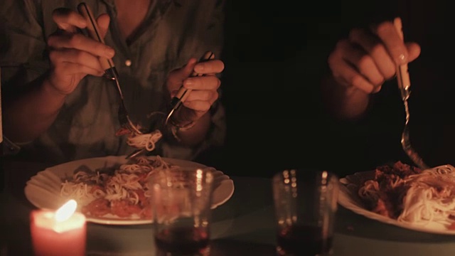 在法国南部的一处露营地，一对年轻情侣在烛光下亲吻、微笑、吃意大利面。视频素材